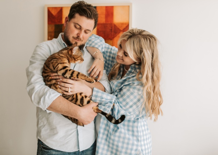 Foto encantadora de um lindo casal compartilhando um momento delicioso com seu gato, retratando a alegria e o amor que os animais de estimação podem trazer aos relacionamentos.