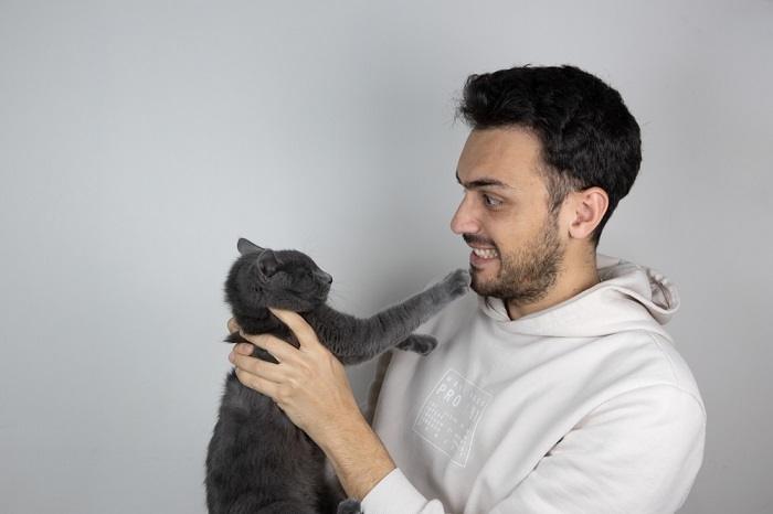 Uma imagem representando um homem interagindo com um gato.