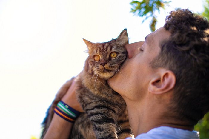 homem no jardim abraçando e beijando um gato