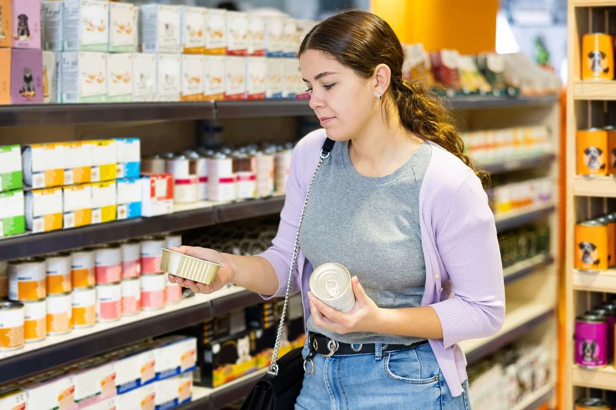 Mulher fazendo compras no corredor de alimentos para animais de estimação